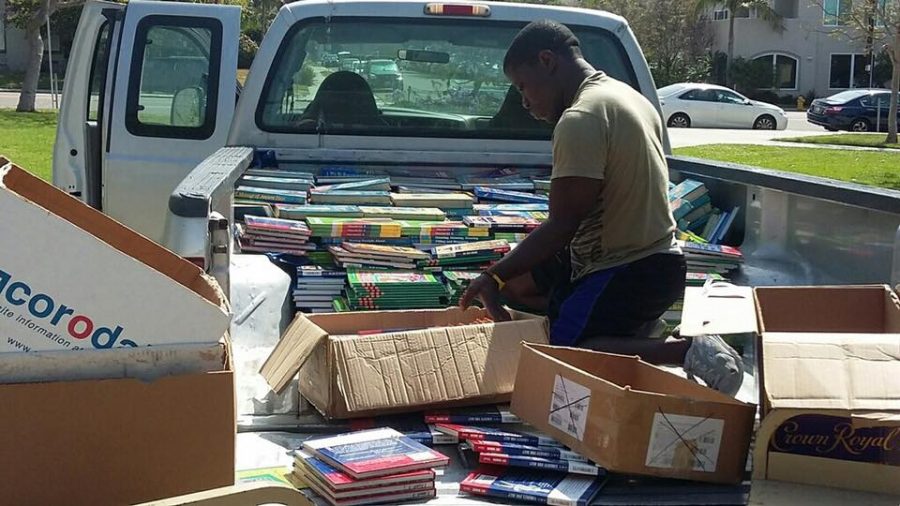 Robert Saah sorting and unloading a donation of books. (Photo Credit to the Compassion For African Villages Facebook page.) 