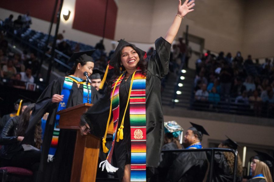 A Mesa student proudly waves during the spring 2019 Commencement Ceremony, now a thing of the past. Photo Credit: Mesa Office of Communications