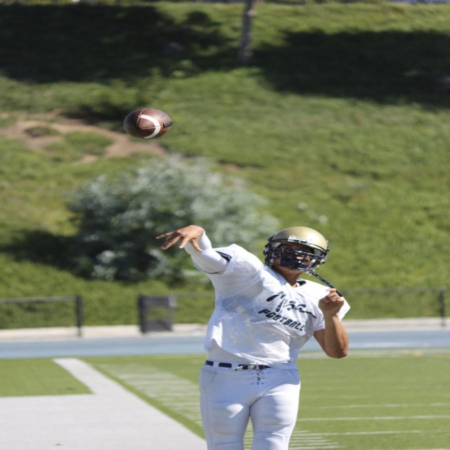 Rodney Alo throwing the football to warm up before practice.