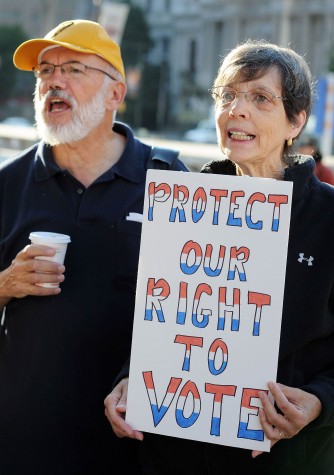 Dennis Brunn and Jill Murray of the Unitarian Society in Philadelphia, Pennsylvania cheer a speaker while holding a sign during a voter ID rally September 13, 2012 in Philadelphia, Pennsylvania. The Pennsylvania Supreme Court held a hearing on Pennsylvania&apos;s state Supreme Court justices on whether a law requiring photo identification from each voter should take effect for the Nov. 6 presidential election. (William Thomas Cain/MCT)