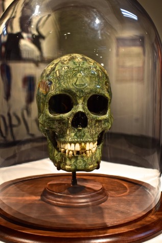 "In God We Trust" Plaster molded skull with clippings of U.S. bills and a gold tooth.