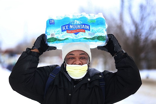 Carl Huntere, 48, of Flint, Mich., walks home through the snow from the North End Soap Kitchen in Flint on Wednesday, Jan. 13, 2016, where he received a case of free bottled water.
Photo Credit: MCT Campus