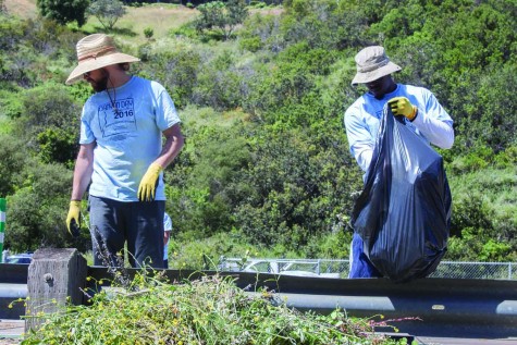 Stephen Adegoke and another volunteer work on clearing bundles of torn up plants