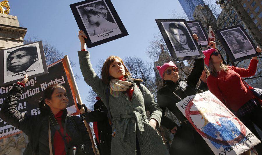 On International Womens Day, about 50 people gather on the edge of Central Park in New York to voice their opposition to the current administration policies. A group holds photographs of women who have died due to illegal abortions or no access to health care. (Carolyn Cole/Los Angeles Times/TNS)