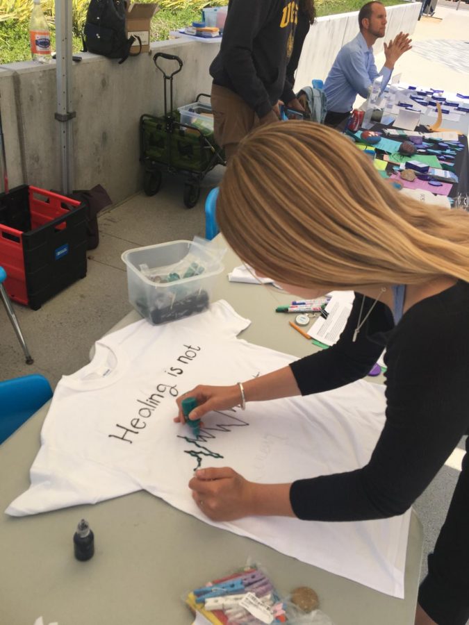 Emily Hanes, student, decorates a t-shirt with a supportive message for the Clothesline Project.
