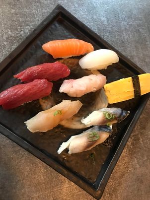 From top to bottom, a salmon nigiri, two tuna nigiri, one squid nigiri, one albacore nigiri, one yellowtail nigiri, one tamago (sweet egg) nigiri, and two mackeral nigiri.
